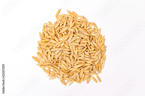 Top view macro imageof unpeeled raw oat pile isolated at white background.