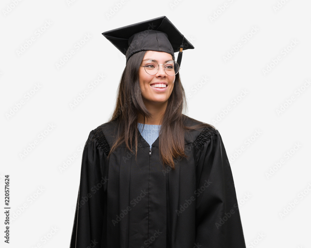 Young hispanic woman wearing graduated cap and uniform looking away to side with smile on face, natural expression. Laughing confident. Young hispanic woman wearing graduated cap and uniform looking away to side with smile on face, natural expression. Laughing confident.