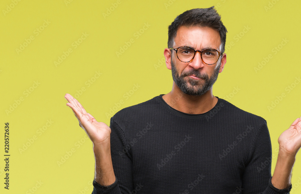 Adult hispanic man wearing glasses over isolated background clueless and confused expression with arms and hands raised. Doubt concept. Adult hispanic man wearing glasses over isolated background clueless and confused expression with arms and hands raised. Doubt concept.
