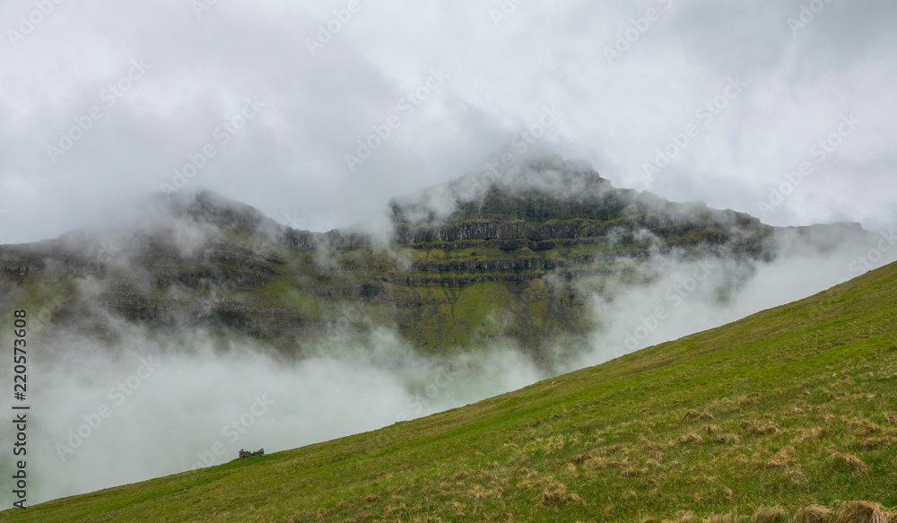 AERIAL: Flying over an empty meadow leading up to grassy mountain on foggy day. AERIAL: Flying over an empty meadow leading up to grassy mountain on foggy day.