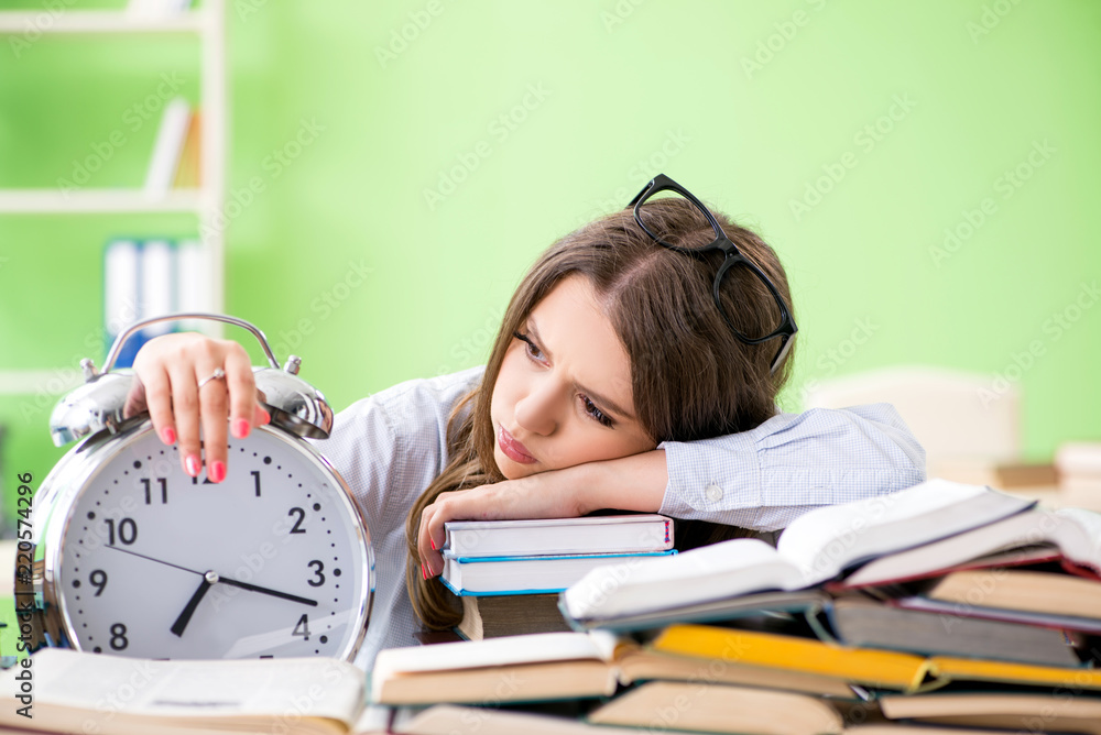 Young female student preparing for exams with many books in time Young female student preparing for exams with many books in time