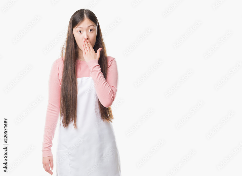 Young Chinese shop owner woman over isolated background wearing white apron cover mouth with hand shocked with shame for mistake, expression of fear, scared in silence, secret concept Young Chinese shop owner woman over isolated background wearing white apron cover mouth with hand shocked with shame for mistake, expression of fear, scared in silence, secret concept