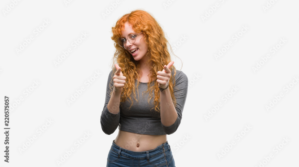 Young redhead woman pointing fingers to camera with happy and funny face. Good energy and vibes. Young redhead woman pointing fingers to camera with happy and funny face. Good energy and vibes.