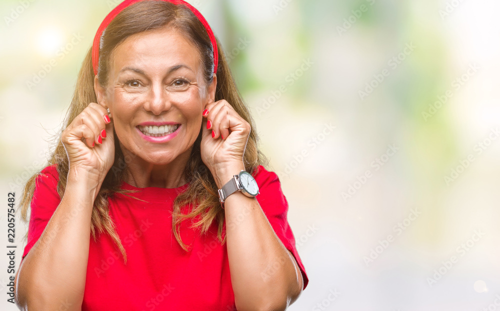 Middle age senior hispanic woman over isolated background covering ears with fingers with annoyed expression for the noise of loud music. Deaf concept. Middle age senior hispanic woman over isolated background covering ears with fingers with annoyed expression for the noise of loud music. Deaf concept.