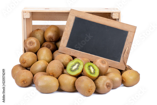 Wooden box filled with many ripe kiwi fruits and two half fruits and a old blank slate blackboard isolated on white background