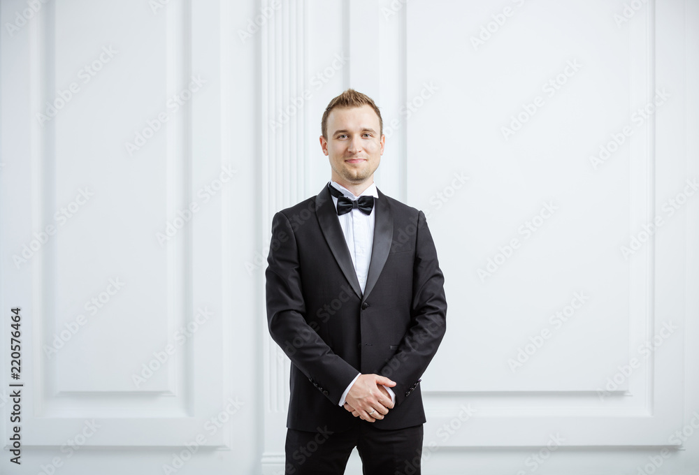 Attractive young man in tuxedo smiling and looking at camera Attractive young man in tuxedo smiling and looking at camera