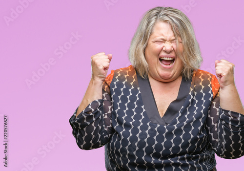 Senior plus size caucasian woman over isolated background crazy and mad shouting and yelling with aggressive expression and arms raised. Frustration concept.