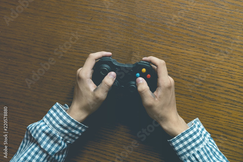 close up person's hands playng video game isolated on wooden table concept