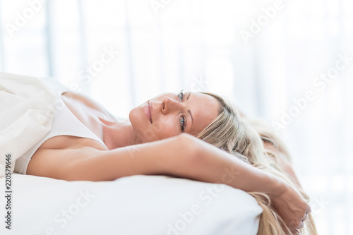 Woman with long blond hair in the bed don't want to wake up in morning