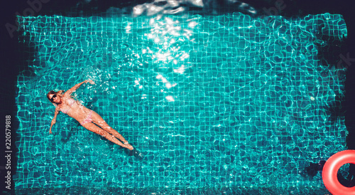 Young pretty slim woman in straw hat on a pink air mattress in the swimming pool