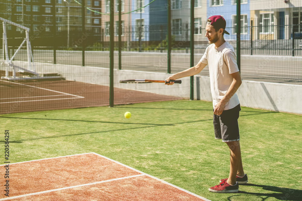 portrait of young man on the summer campus school tennis court