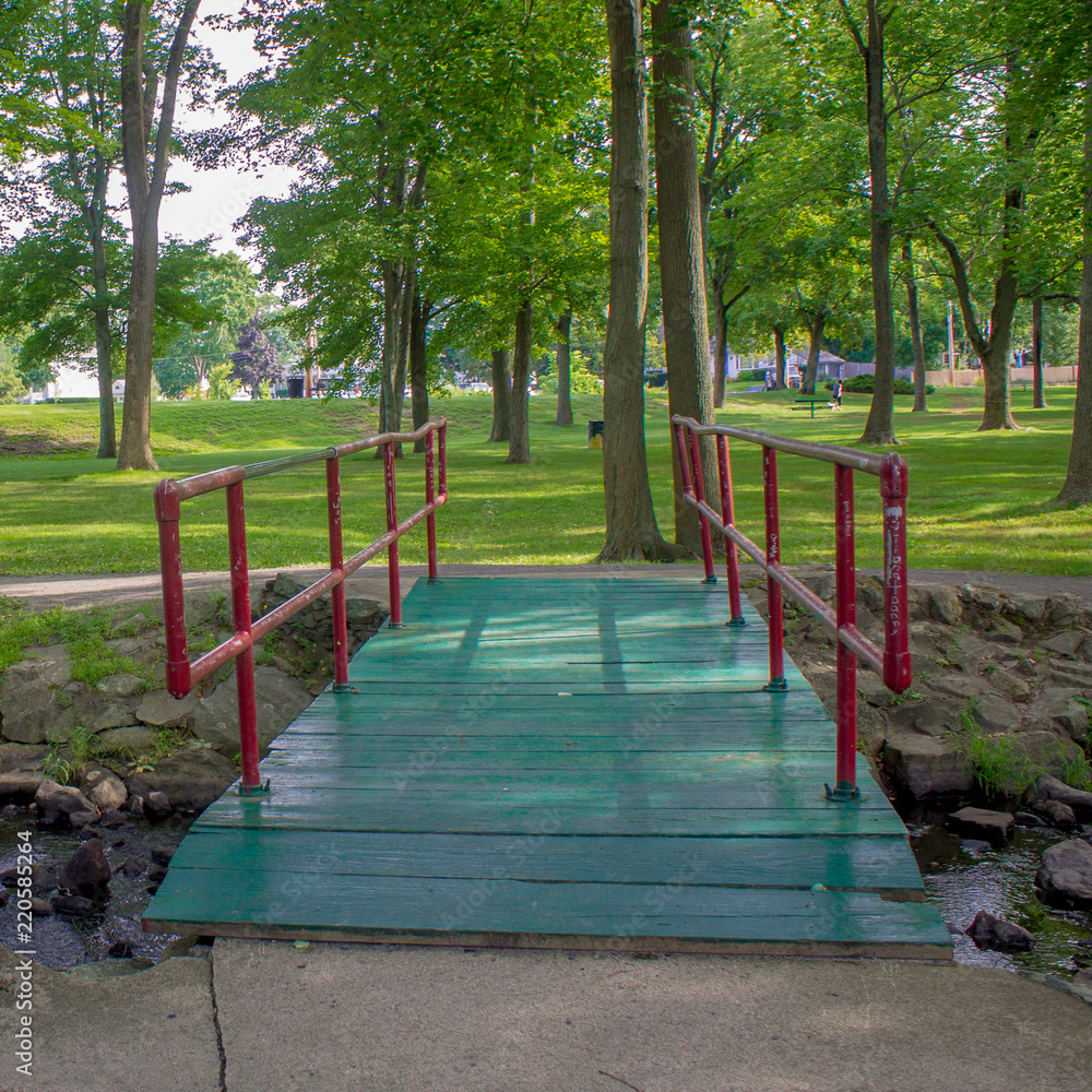 Green and red old bridge over stream