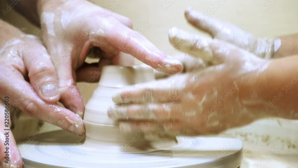 hands of adult man and child making a clay pot hands of adult man and child making a clay pot