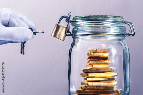 Concept of burglary and theft of money. Hand in gloves with keys and container with gold. photo