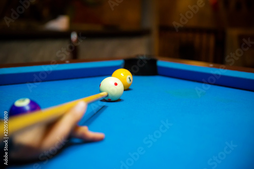 Fotografi Pool balls on the blue felt pool table with player hands and pool cue stick