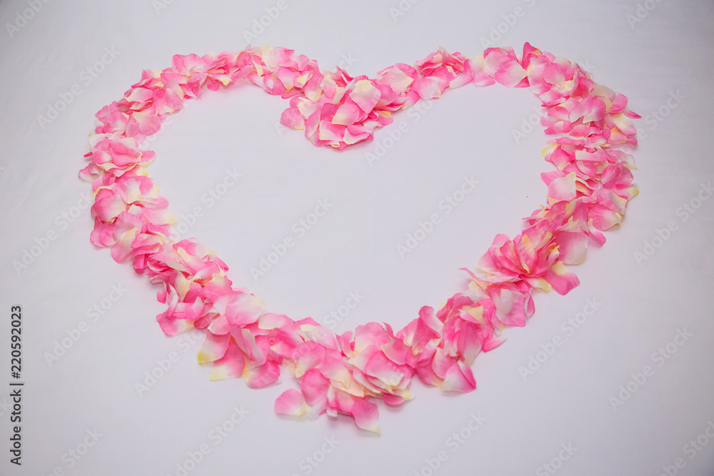 Close up heart shape from pink rose petals on the white bed. honeymoon suite room decoration. luxury suite. holidays with valentine theme. image for valentine day, honeymoon period and love symbol. 