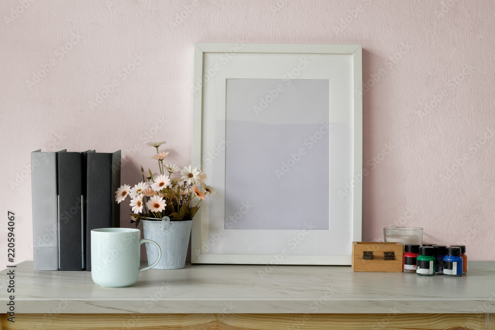 Mockup poster frame, books, dry flower and coffee mug on white desk. Mockup poster frame, books, dry flower and coffee mug on white desk.