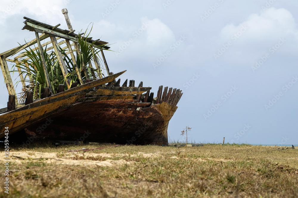 Abandon shipwreck near the sea shore under blue sky background and bright sun