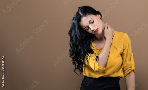 Young woman suffering from neck pain on a solid background