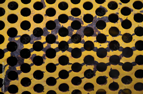 Closeup abstract yellow metal grill with holes pattern 