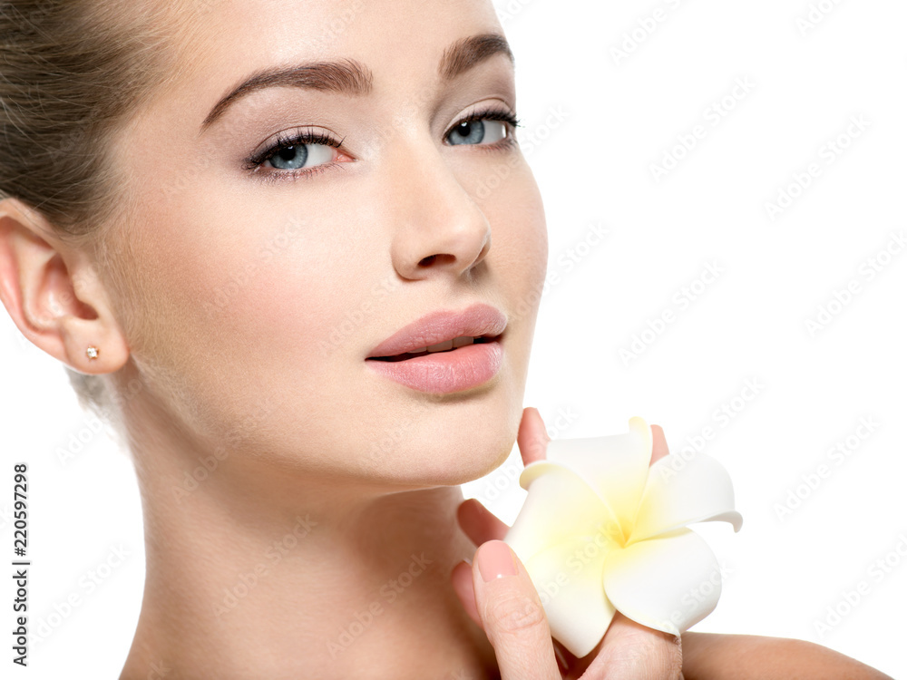 Beautiful young woman with flower in hand near at face. Beautiful young woman with flower in hand near at face.