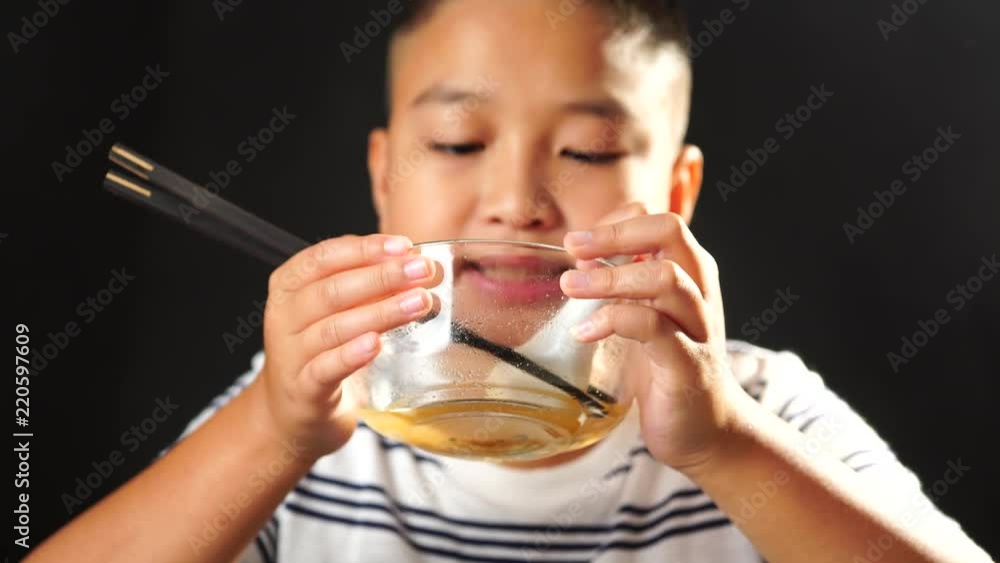 4k Young Asian Thai boy eat instant noodle in a glass bowl on black backgound. 4k Young Asian Thai boy eat instant noodle in a glass bowl on black backgound.