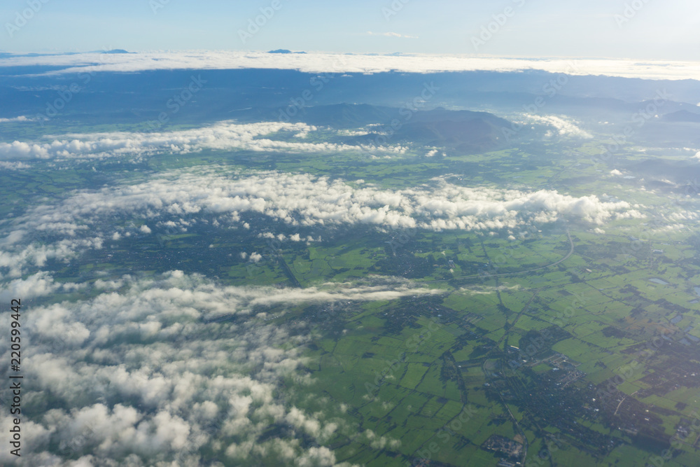 View cloud and city scape through cloud hole in plane window seen.