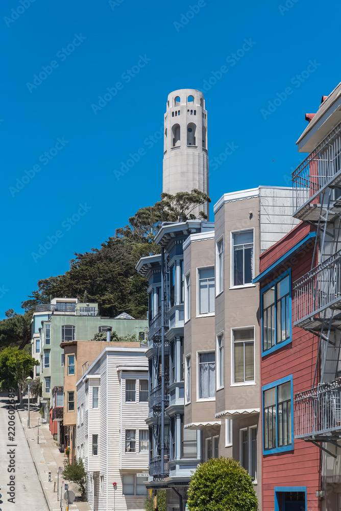San Francisco, typical colorful houses in Telegraph Hill, sloping street, with the Coit tower in background 
