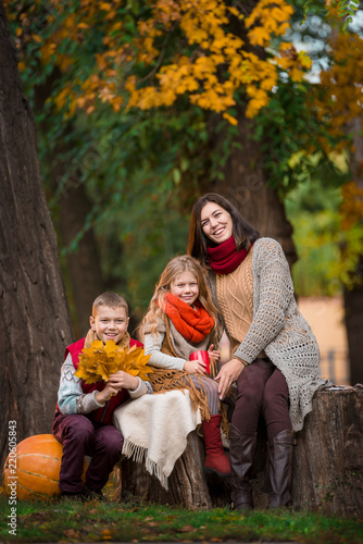 Mother, son, daughter sitting on the large pumpkin in autumn park