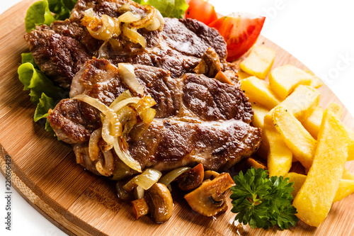Grilled steak with french fries and vegetables on white background