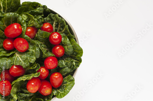 Isolated shot of some leafy green and tomatoes in a metal bowl