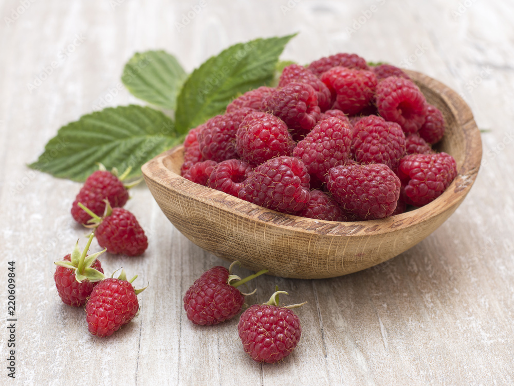 raspberry in a wooden plate on a kitchen table. raspberry in a wooden plate on a kitchen table.