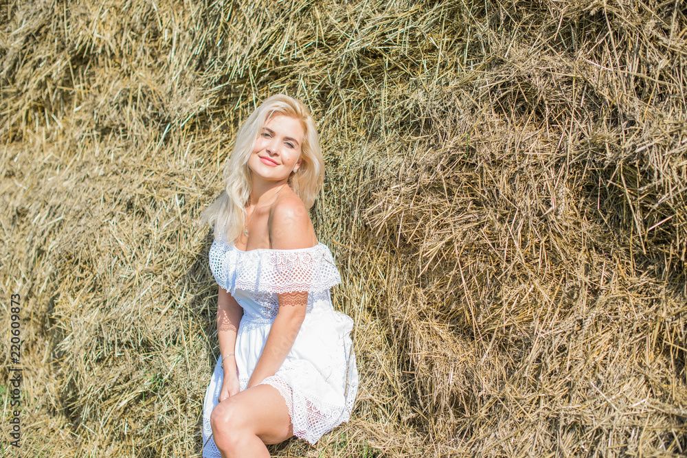 Nature time vacation and people concept - young woman dreaming on cereal field. . Beauty romantic girl outdoors against hay stack. Photo of sexy blonde in a field with haystacks Nature time vacation and people concept - young woman dreaming on cereal field. . Beauty romantic girl outdoors against hay stack. Photo of sexy blonde in a field with haystacks