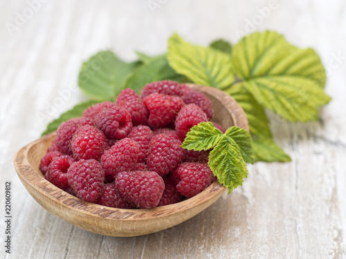 raspberry in a wooden plate on a kitchen table. 