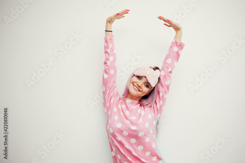 portrait of cute young woman in pajamas and sleep mask, stretches. Woke up in the morning