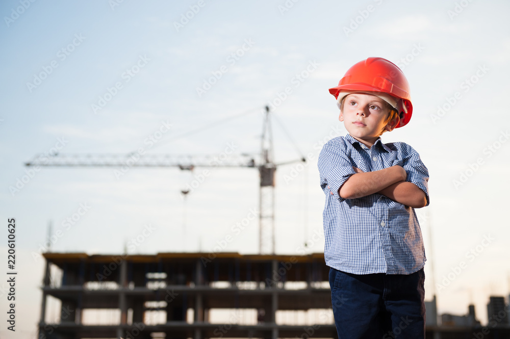 handsome american kid in orange helmet on construction site with high crane handsome american kid in orange helmet on construction site with high crane