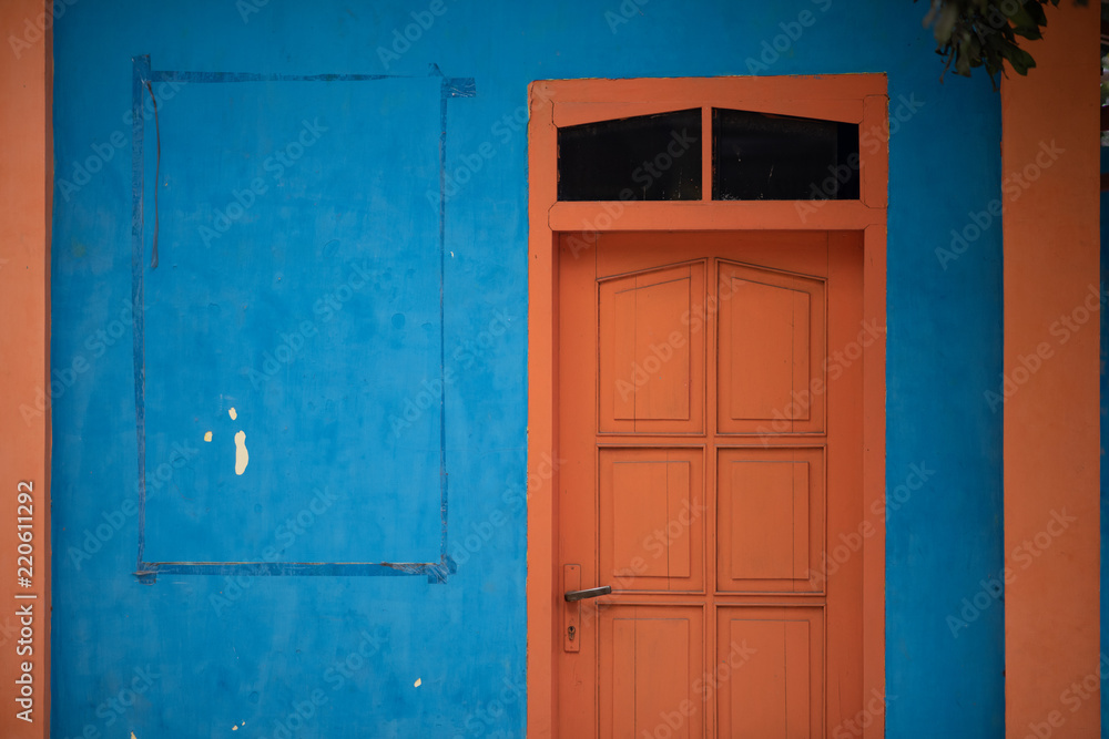 old orange door in blue wall