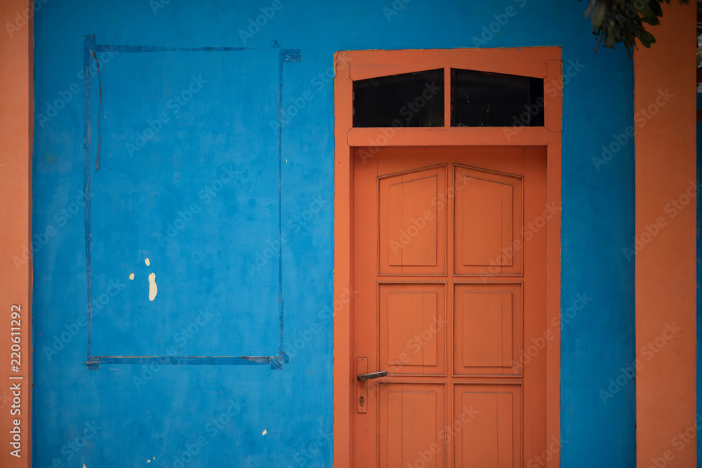 old orange door in blue wall old orange door in blue wall