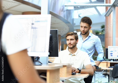 Group of young confident business people analyzing data using computer while spending time in the office.