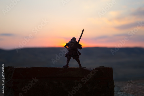 Fighter with a sword silhouette a sky ninja. Samurai on top of mountain with dark toned foggy background