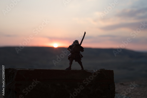 Fighter with a sword silhouette a sky ninja. Samurai on top of mountain with dark toned foggy background