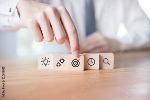 Businessman hand arranging wood block with icon business strategy and Action plan.