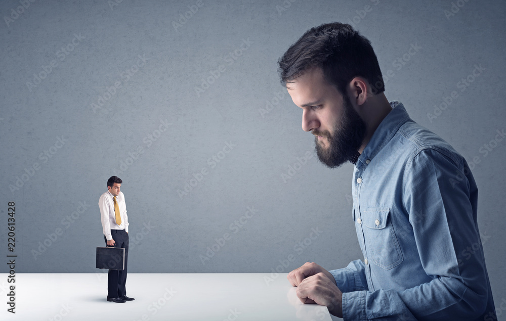 Young professional businessman being angry with an other miniature businessman Young professional businessman being angry with an other miniature businessman
