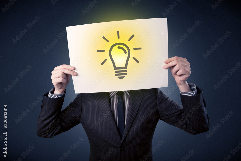 Young businessman hiding behind a lightbulb drawn on paper Young businessman hiding behind a lightbulb drawn on paper