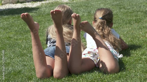 Little girls barefoot lying on the lawn on a warm summer day. photo