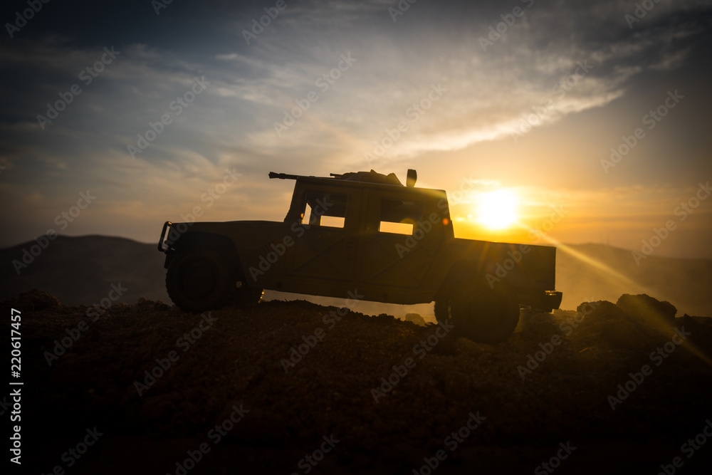 Fototapeta premium Military patrol car on sunset background. Army war concept. Silhouette of armored vehicle with gun in action. Decorated.