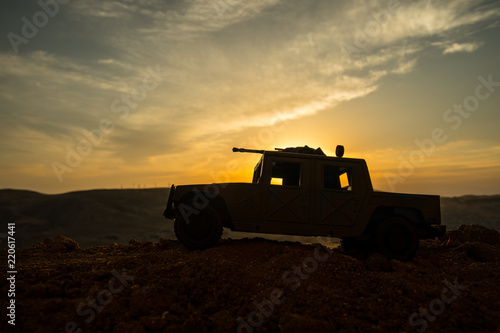 Military patrol car on sunset background. Army war concept. Silhouette of armored vehicle with gun in action. Decorated. © zef art