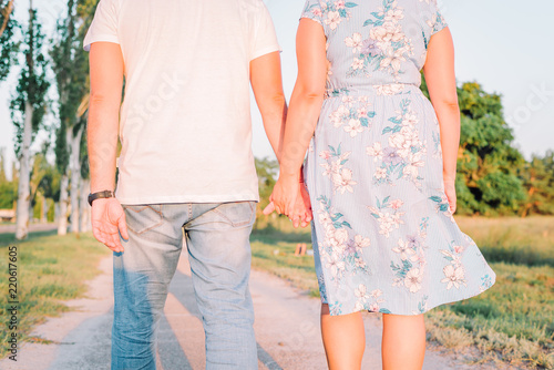 Quadro su tela Cute young couple in love is holding their hands and walking in the park