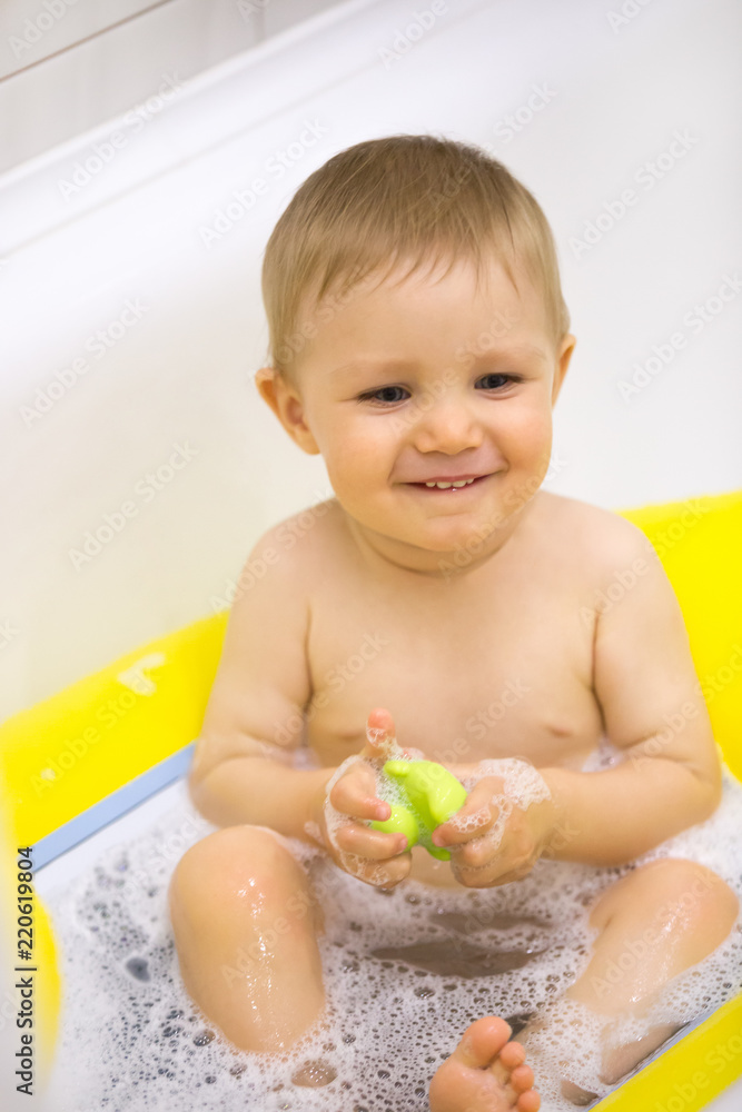 Cute little kid taking bath with foam and rubber duck, smiling toddler having fun washing in bathroom, happy child laughing and playing in bathtub, excited small baby enjoying splashing in washroom Cute little kid taking bath with foam and rubber duck, smiling toddler having fun washing in bathroom, happy child laughing and playing in bathtub, excited small baby enjoying splashing in washroom