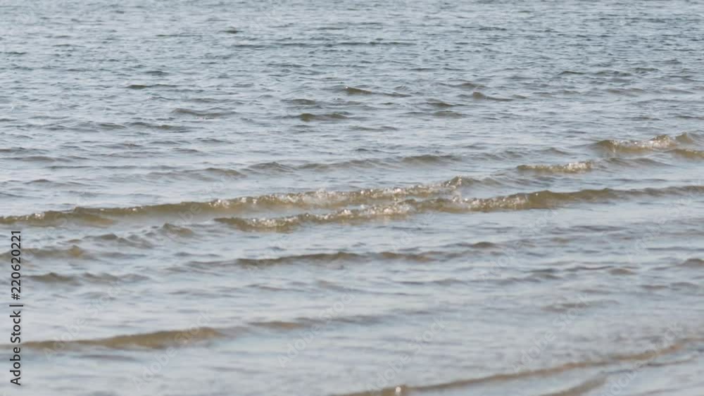 Slow motion handheld closeup of small waves on a beach on a sunny day Slow motion handheld closeup of small waves on a beach on a sunny day